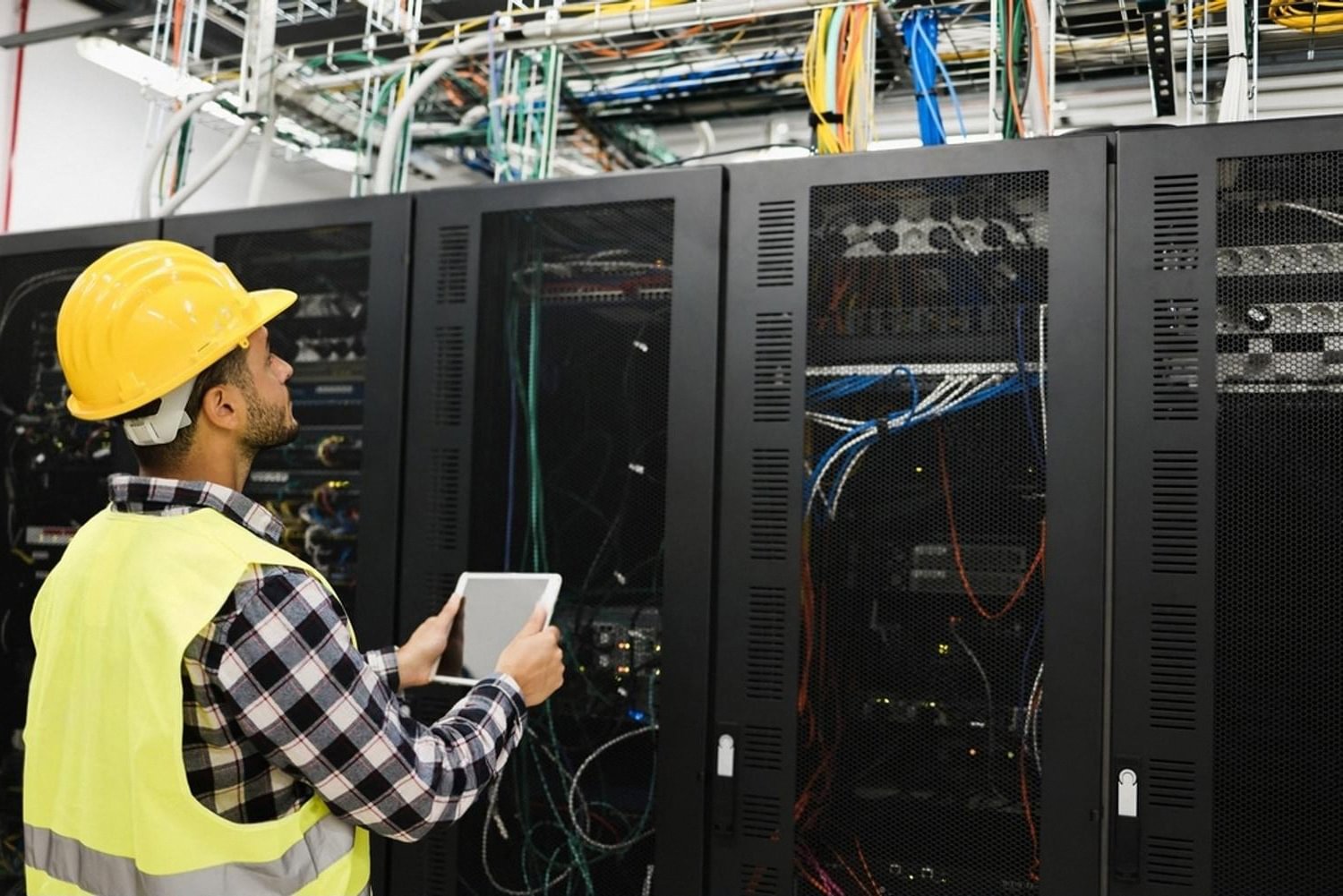 IT engineer in safety gear inspecting server racks inside a data center
